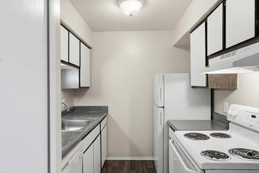 A small kitchen with white appliances and a black and white cabinet.