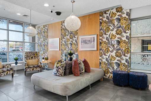 A living room with a sofa, chairs, and a large floral wallpaper.