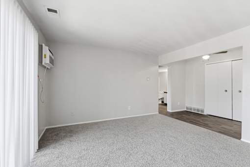 A white room with a carpeted floor and a television mounted on the wall.
