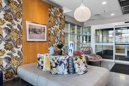 A living room with a grey sofa and a floral wallpaper.