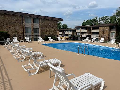 A row of white chairs are lined up on a tan pool deck.