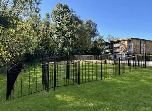 A black metal fence surrounds a green lawn.