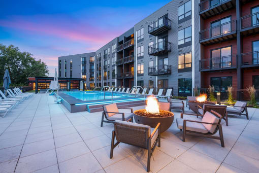 an outdoor pool with chairs and a fire pit at dusk