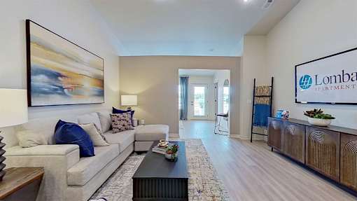 A spacious living room with a couch, coffee table, and a painting on the wall.