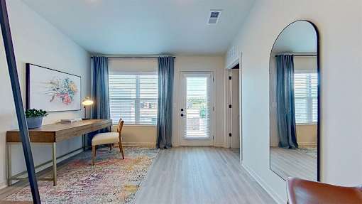 Interior picture of a bright, neutral front room with a door and large window.