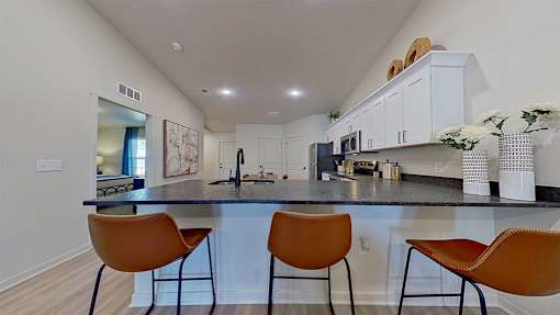 Stools against the kitchen breakfast bar with gooseneck sink.
