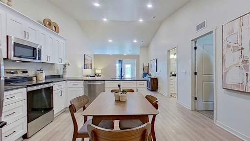 A wide angle shot of the kitchen and dining area showcasing vaulted ceilings.