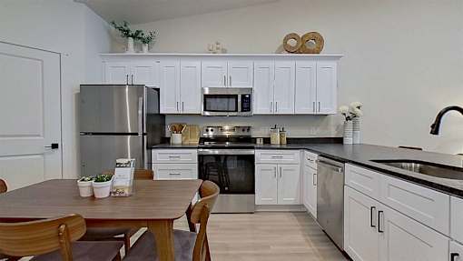 Kitchen with white cabinetry, stainless steel appliances, and dark modern countertops