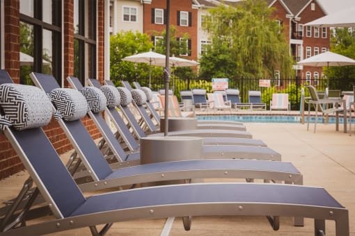a row of chaise lounges in front of a pool with umbrellas