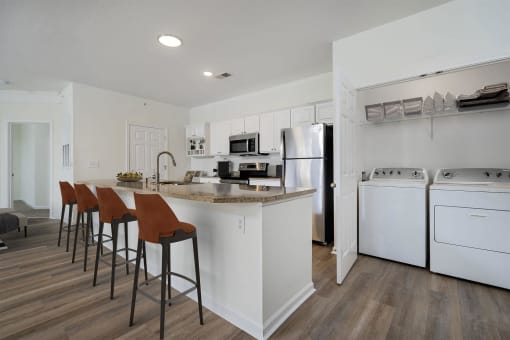 a kitchen with white appliances and a counter with stools