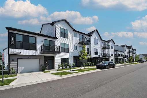 A row of modern townhouses with a car parked on the street.