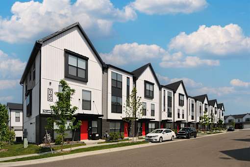 A row of modern houses with cars parked in front.