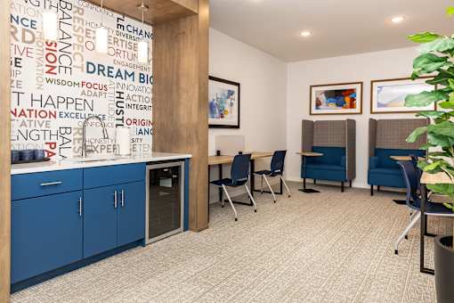 A room with a wall covered in words like "dream" and "innovation" and a fridge in the corner.