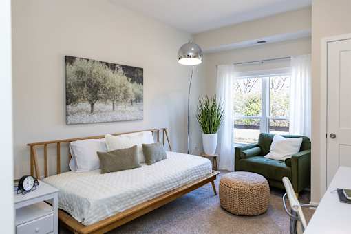 A bedroom with a bed, a chair, and a painting on the wall.