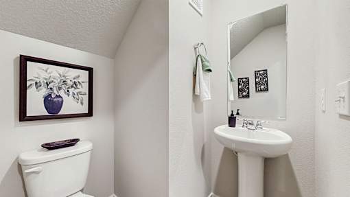 A white toilet sits next to a white sink in a small bathroom.