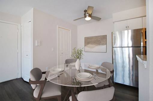 A modern dining room with a glass table and chairs.