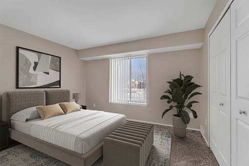 A bedroom with a large bed and a potted plant.