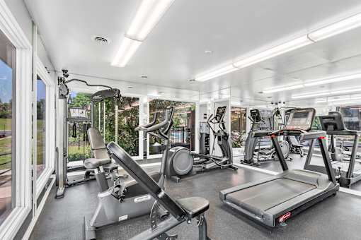 A well-lit gym with treadmills, exercise bikes, and other equipment.