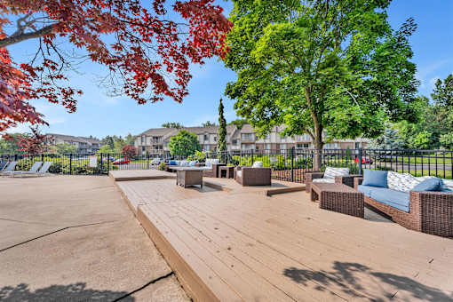 A wooden deck with a bench and trees in the background.