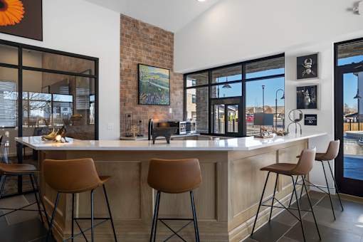 A modern kitchen with a bar area and chairs.