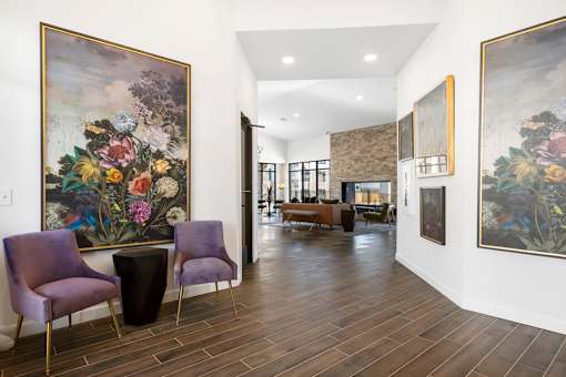 A room with a purple chair and a painting of flowers on the wall.
