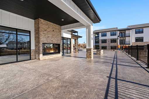 A modern building with a stone fireplace and a long concrete patio.