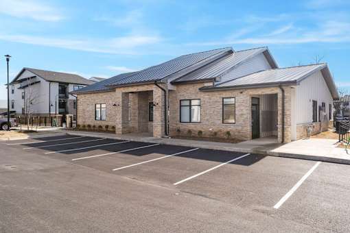 A parking lot in front of a building with a grey roof.
