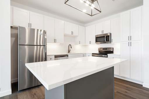 A kitchen with a white countertop and stainless steel appliances.