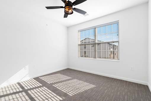 A room with a ceiling fan and a window with blinds.
