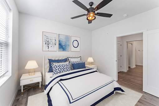A bedroom with a bed, two lamps, and a ceiling fan.
