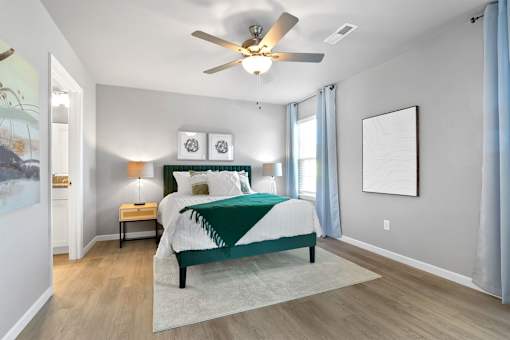 A bedroom with a bed, nightstand, and a ceiling fan.