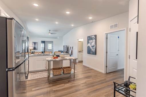 A modern kitchen with a refrigerator on the left and a dining table in the middle.