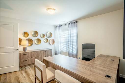 A room with a desk, chairs, and a wall decoration.