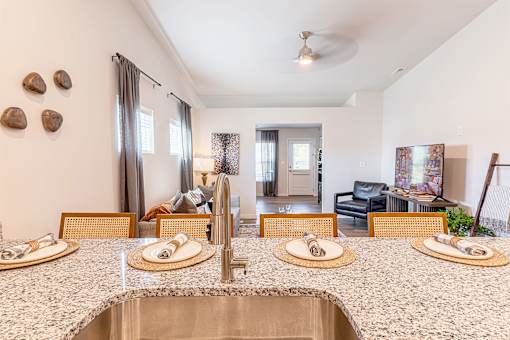 A kitchen with a sink, counter and chairs.