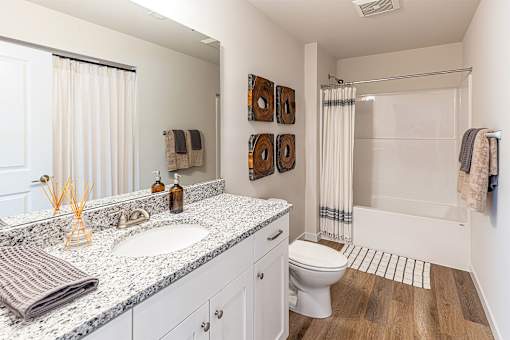 A bathroom with a white toilet, a sink with a marble countertop, and a shower area.