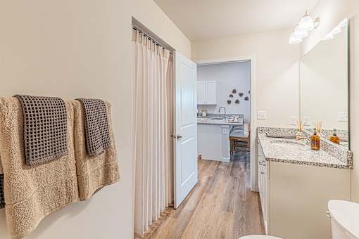 A bathroom with a white tub and a sink with a granite countertop.