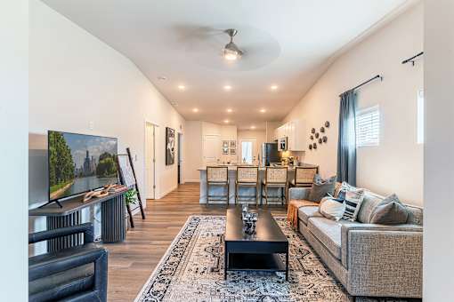 A living room with a grey couch, a black coffee table, and a painting of a landscape on the wall.