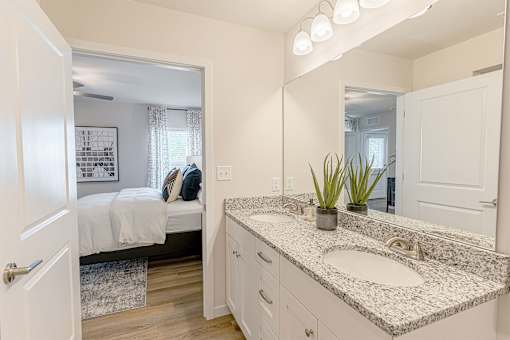 A bathroom with a white countertop and a mirror above it.
