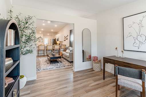 A living room with a wooden floor and a painting on the wall.