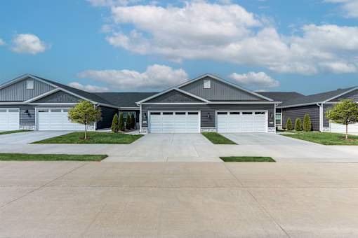 A large, modern house with a grey roof and multiple garages.