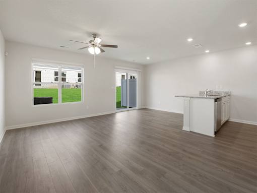 A spacious room with a ceiling fan and a kitchenette.