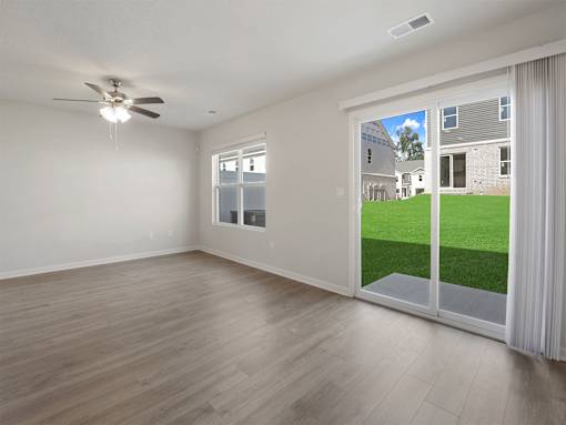 A room with a ceiling fan and sliding glass doors.