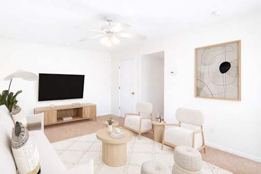 A living room with a white couch, a coffee table, and a television.