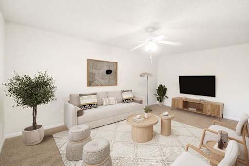 A living room with a white couch, a tree, a coffee table, and a television.