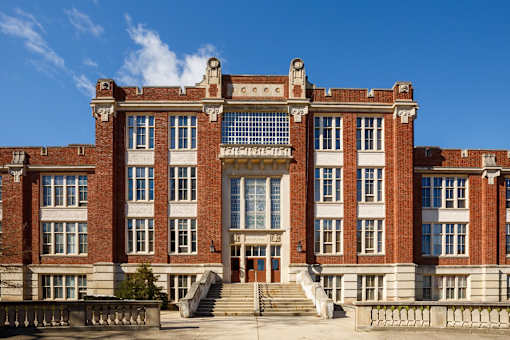 A large red brick building with a central entrance and steps leading up to it.