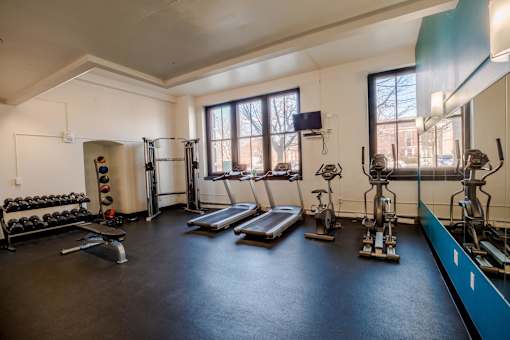 A gym with a variety of equipment including a treadmill, weights, and a bench press.