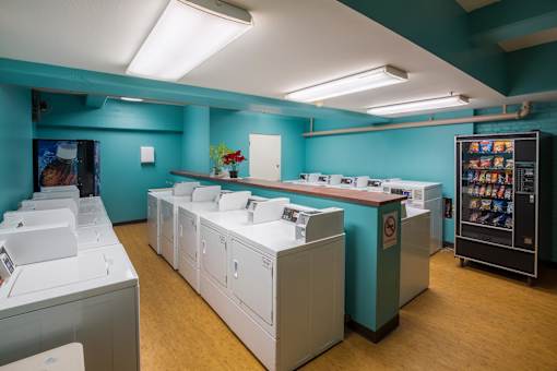 A laundromat with washers and dryers is shown.