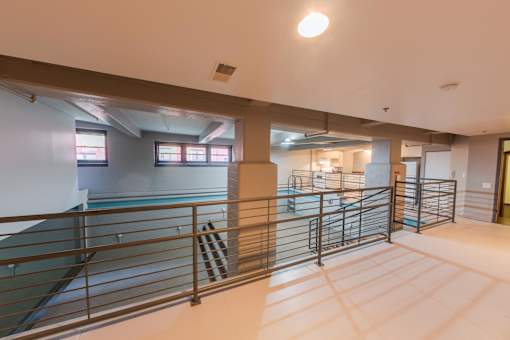 A spacious indoor area with a metal railing and a pool in the background.