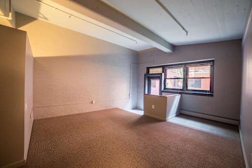 A room with a laptop on a box near a window.