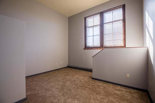 A room with a window and a carpeted floor.